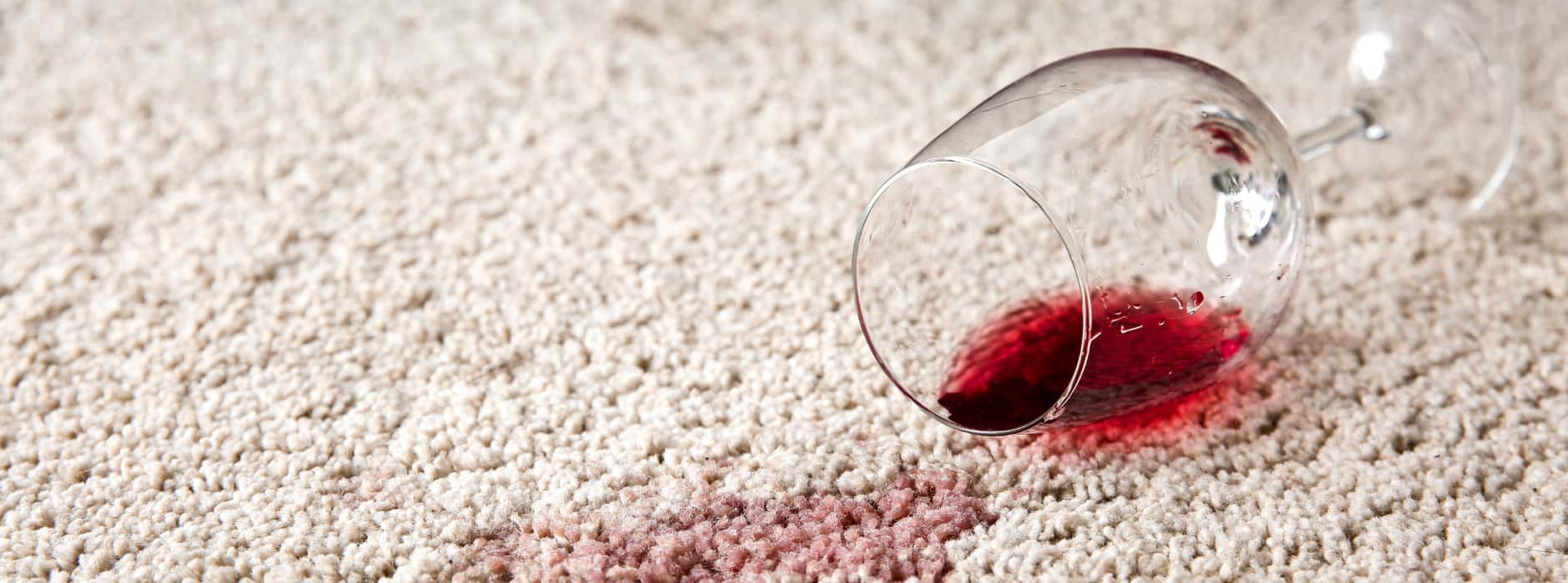 This is a photo of Abbots Langley Carpet Cleaning red wine which has been spilt on a cream carpet. The glass is on its side